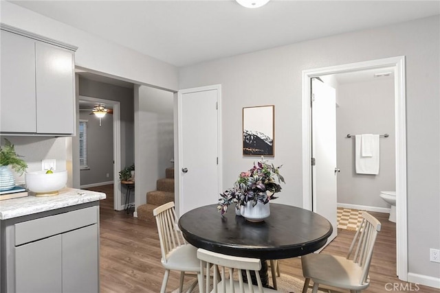 dining room with light wood finished floors, stairway, and baseboards