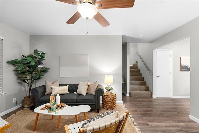 living room with stairway, a ceiling fan, baseboards, and wood finished floors