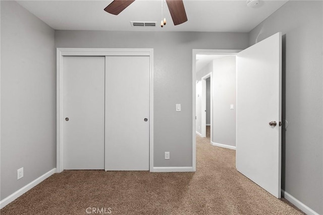 unfurnished bedroom featuring visible vents, a closet, carpet floors, baseboards, and ceiling fan