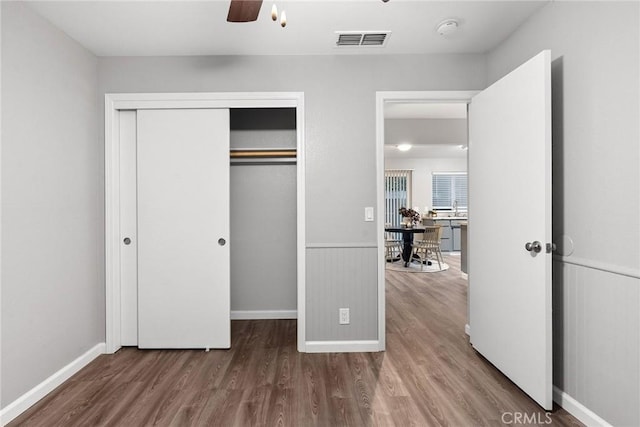 unfurnished bedroom with visible vents, baseboards, a closet, and wood finished floors