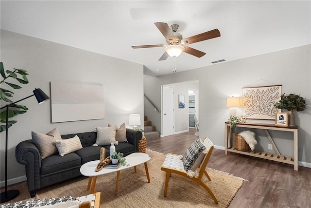 living room with stairs, wood finished floors, visible vents, and ceiling fan