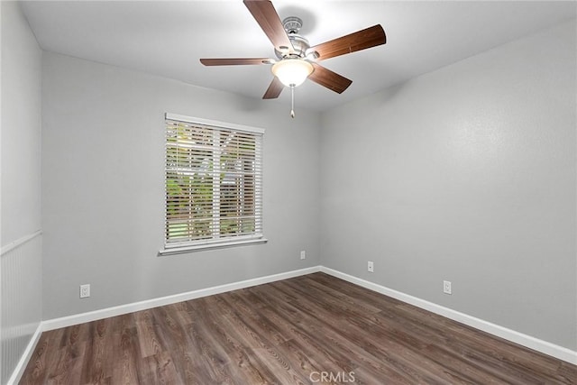 spare room featuring dark wood finished floors, ceiling fan, and baseboards