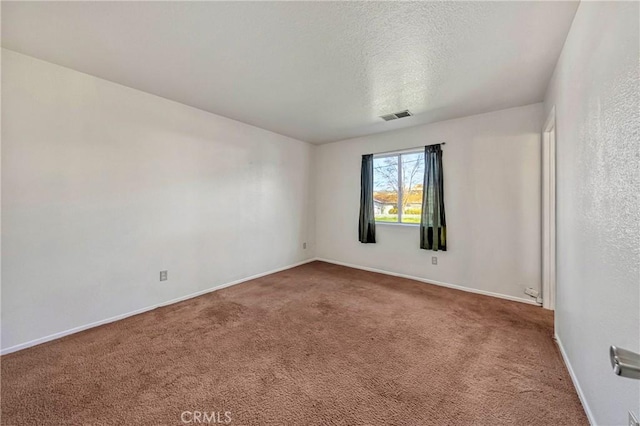 carpeted empty room featuring visible vents, a textured ceiling, and baseboards