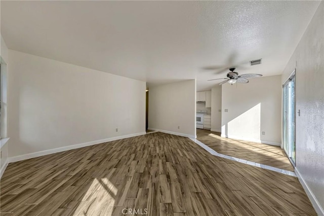 unfurnished living room featuring visible vents, baseboards, ceiling fan, and wood finished floors