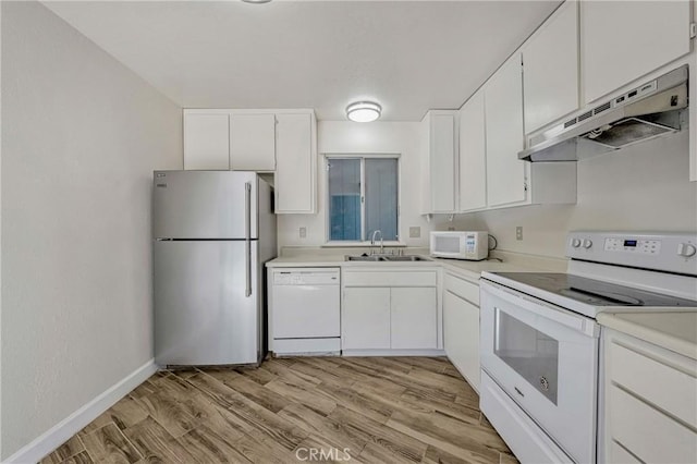 kitchen featuring white appliances, a sink, light countertops, light wood-style floors, and under cabinet range hood