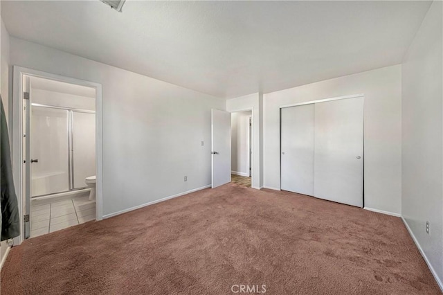 unfurnished bedroom featuring ensuite bathroom, baseboards, a closet, and carpet floors