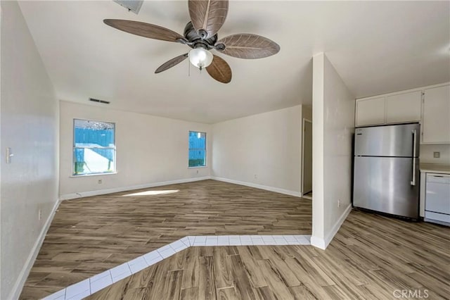 unfurnished living room featuring visible vents, ceiling fan, baseboards, and wood finished floors