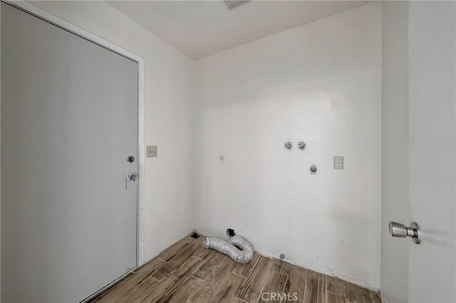 washroom with hookup for an electric dryer, wood finished floors, and laundry area