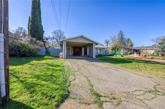 view of front of home with aphalt driveway, a carport, a front yard, and fence