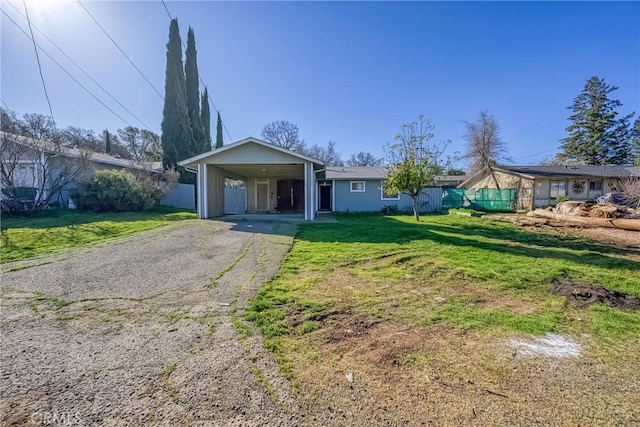 single story home with an attached carport, aphalt driveway, fence, and a front lawn