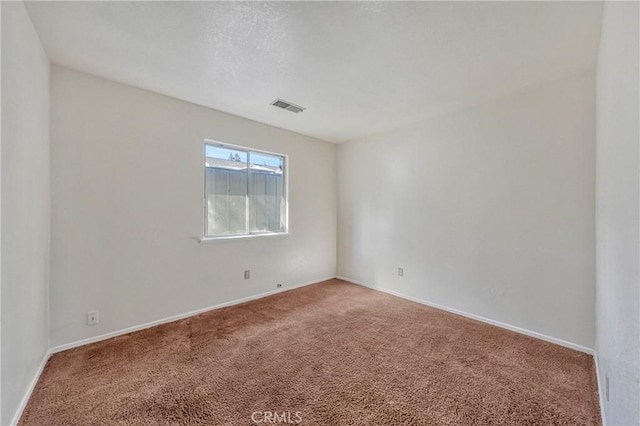 unfurnished room with carpet, visible vents, and baseboards