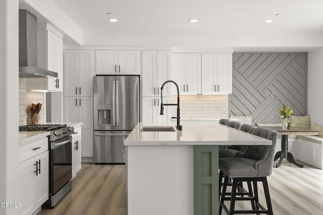 3012 Dunkirk Dr, Oxnard, CA 93035 - kitchen featuring a sink, wall chimney range hood, white cabinetry, stainless steel appliances, and light wood finished floors