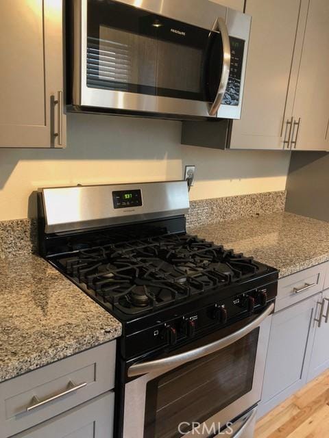 kitchen with light stone counters, stainless steel appliances, and light wood-style flooring