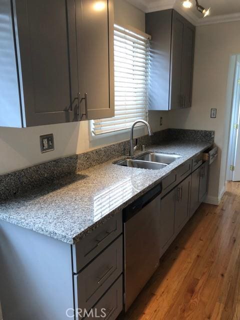 kitchen featuring gray cabinets, a sink, stainless steel dishwasher, crown molding, and light wood finished floors