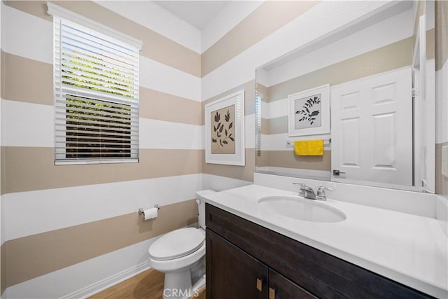 half bathroom featuring vanity, toilet, and wood finished floors