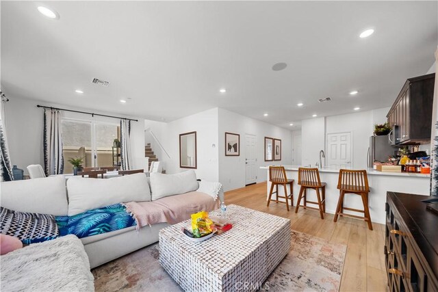 living area featuring stairs, recessed lighting, visible vents, and light wood finished floors