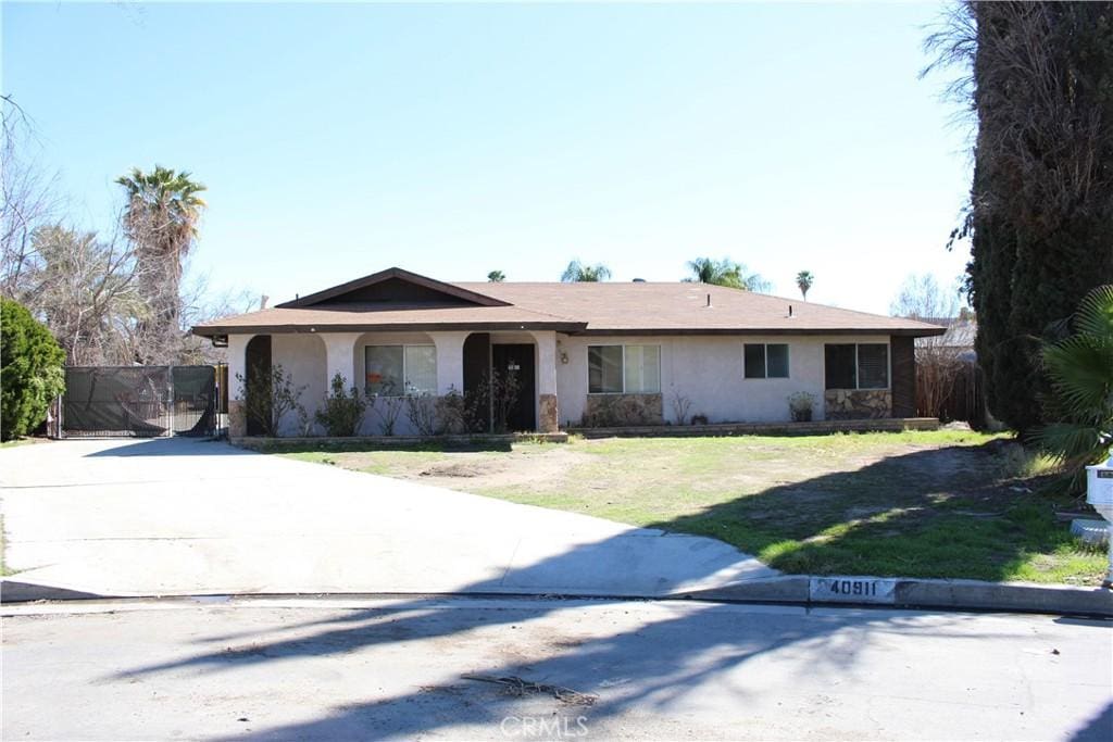 ranch-style home with stucco siding, concrete driveway, and a front lawn