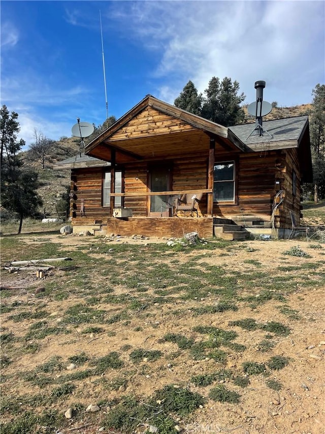 view of front of house featuring log siding, an exterior structure, and an outbuilding