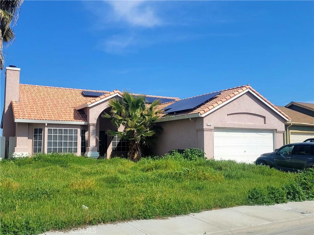 ranch-style home with stucco siding, a garage, a chimney, and a tiled roof