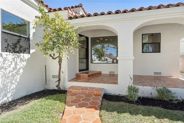 doorway to property featuring crawl space, stucco siding, visible vents, and a tiled roof