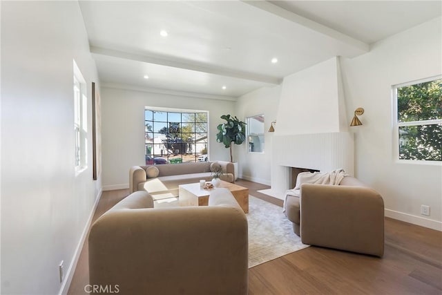 living area with beam ceiling, a fireplace, baseboards, and wood finished floors