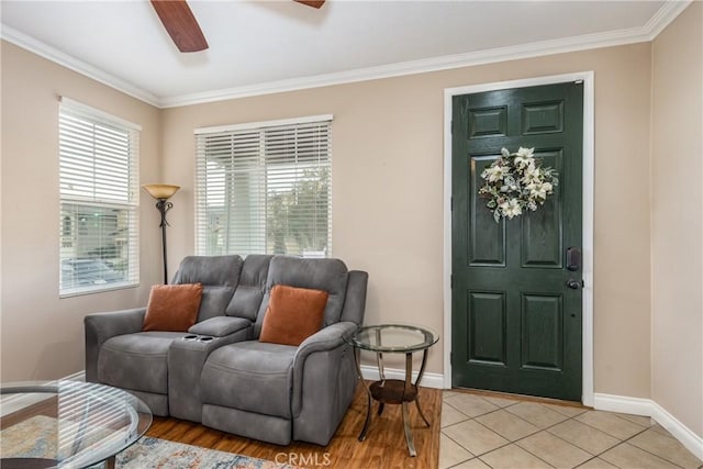 living room featuring light tile patterned floors, baseboards, ceiling fan, and crown molding