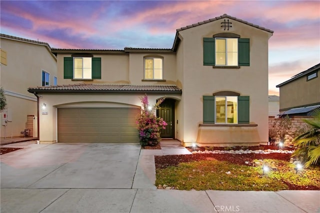 mediterranean / spanish house with stucco siding, driveway, and a tile roof