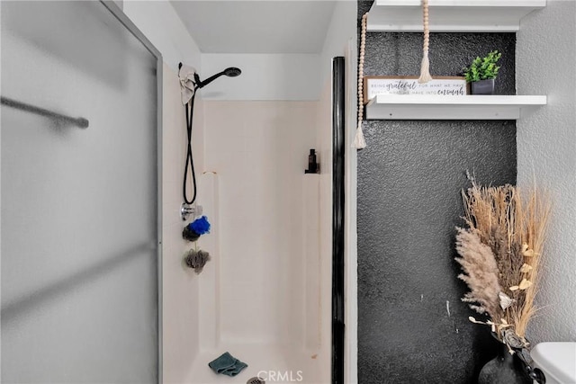 full bathroom with a textured wall and a stall shower