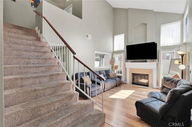 living room with stairway, wood finished floors, visible vents, and a wealth of natural light