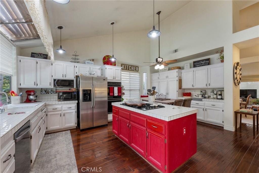 kitchen featuring a sink, appliances with stainless steel finishes, white cabinets, and tile countertops