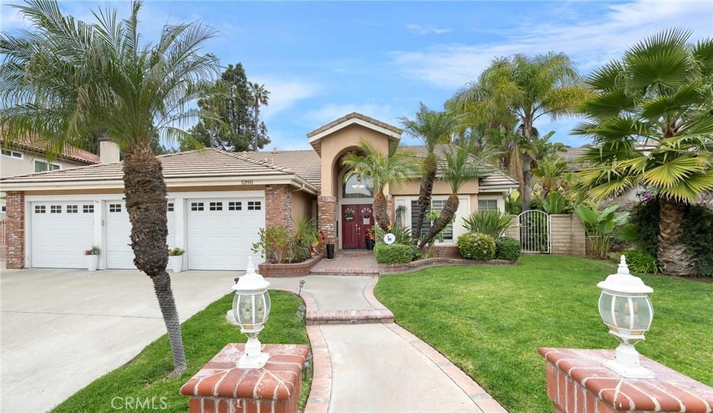 view of front of house featuring a front lawn, a tile roof, a garage, driveway, and a gate