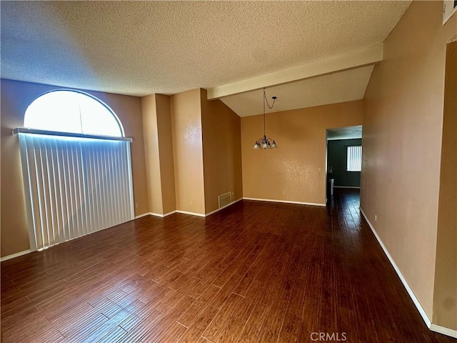 spare room featuring a wealth of natural light, visible vents, wood finished floors, and vaulted ceiling