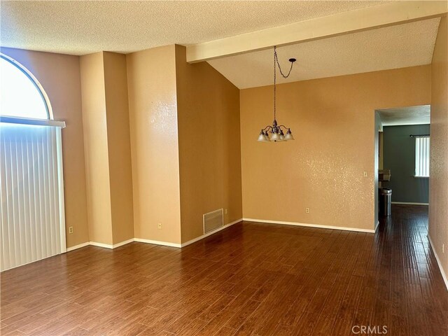 unfurnished room featuring lofted ceiling with beams, wood finished floors, and a textured ceiling