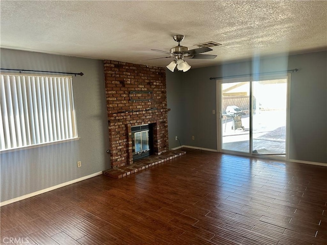 unfurnished living room with a brick fireplace, wood finished floors, visible vents, and baseboards