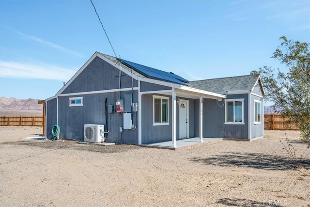 back of house featuring ac unit, a mountain view, solar panels, and fence