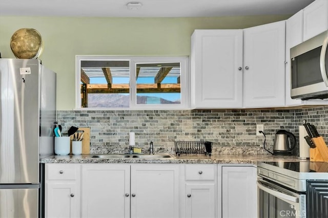 kitchen with decorative backsplash, white cabinets, and stainless steel appliances