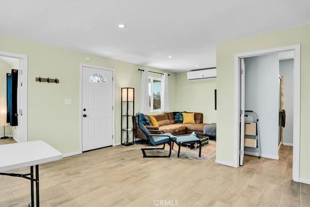 living area featuring recessed lighting, light wood-style flooring, baseboards, and a wall unit AC