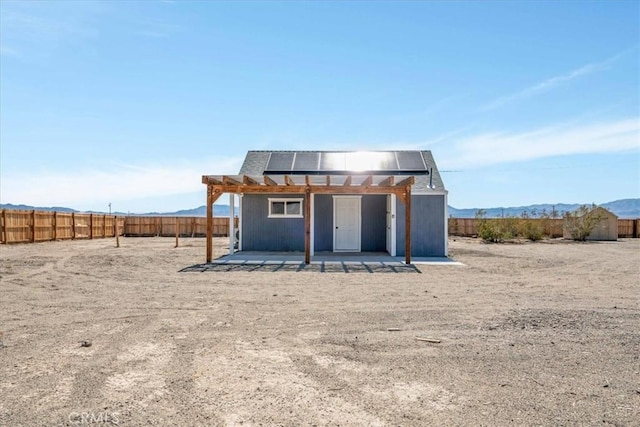 view of outbuilding with solar panels, a mountain view, and a fenced backyard