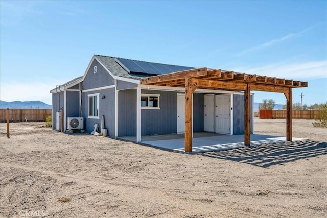 rear view of property featuring roof mounted solar panels, ac unit, and fence