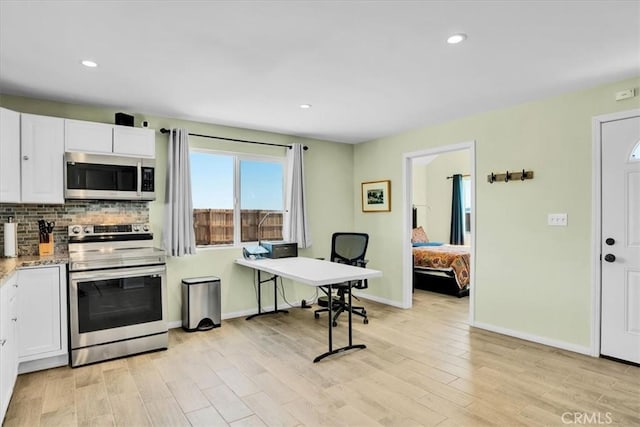 kitchen with light wood-style floors, stainless steel appliances, tasteful backsplash, and white cabinetry