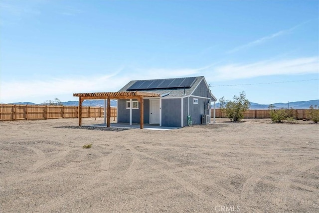 view of outbuilding featuring central AC, a mountain view, solar panels, and a fenced backyard