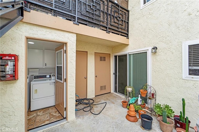 entrance to property with stucco siding, washer / clothes dryer, and visible vents