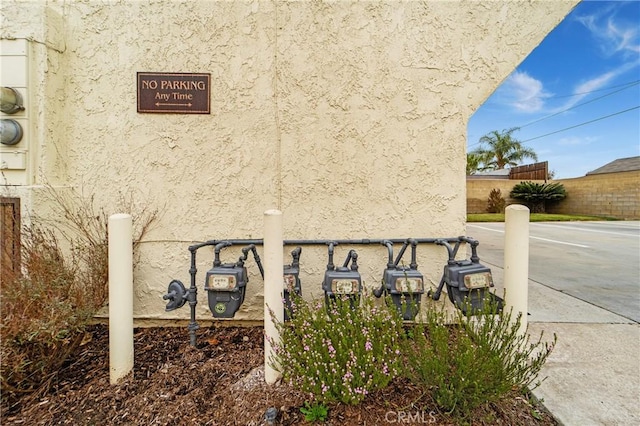 details featuring stucco siding, fence, and gas meter