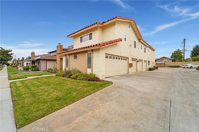 mediterranean / spanish house with an attached garage, a front lawn, a tiled roof, stucco siding, and driveway