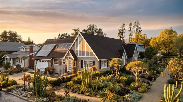 view of front of home featuring a garage, driveway, roof mounted solar panels, and stucco siding