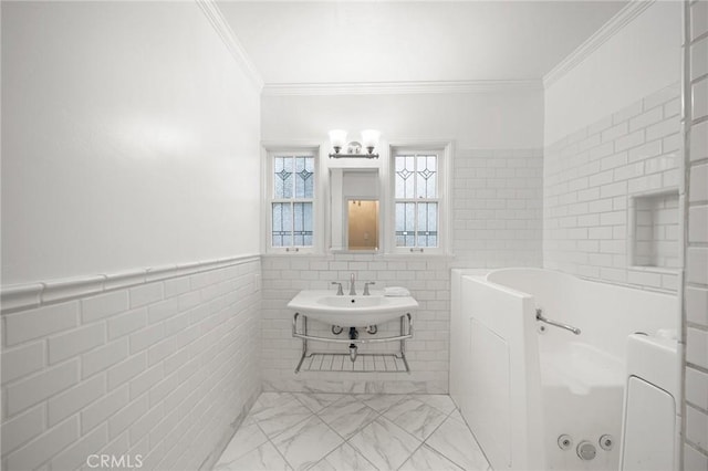 full bath featuring a sink, ornamental molding, wainscoting, tile walls, and a jetted tub