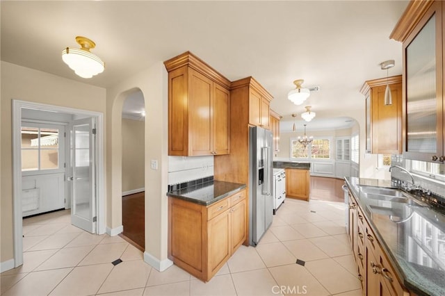 kitchen with arched walkways, a sink, light tile patterned flooring, and stainless steel fridge with ice dispenser