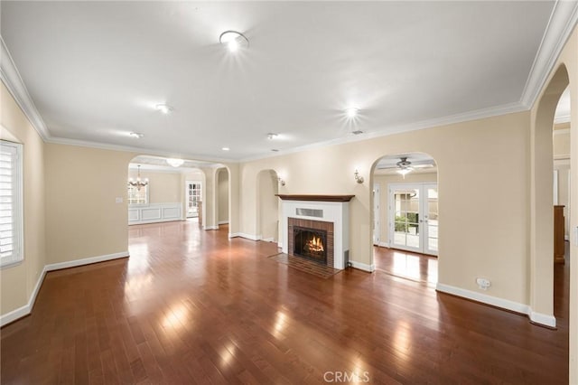 unfurnished living room with arched walkways, wood finished floors, and a fireplace