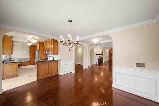 kitchen featuring dark wood-type flooring, stainless steel microwave, dark countertops, open floor plan, and brown cabinetry