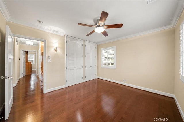 unfurnished bedroom with crown molding, wood finished floors, baseboards, and ceiling fan